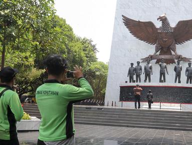 Pengunjung berfoto di depan Monumen Pancasila Sakti, Jakarta Timur, Selasa (1/10/2024). (Liputan6.com/Herman Zakharia)