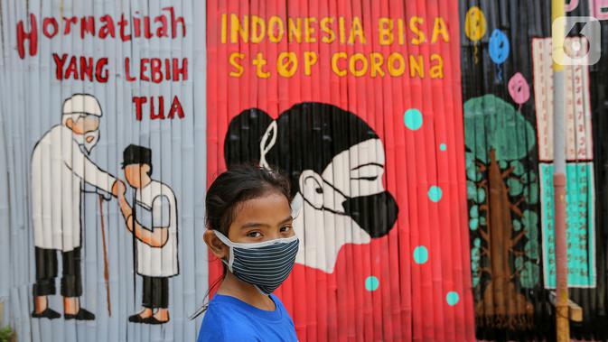 Seorang anak kenakan masker dengan latar belakang mural Indonesia Bisa Stop Corona di Lapangan Bulutangkis, Kampung Kali Pasir, Jakarta, Selasa (7/4/2020). Pesan mural mengajak warga untuk memutus rantai penyebaran Corona Covid-19 dengan diam di rumah. (Liputan6.com/Fery Pradolo)