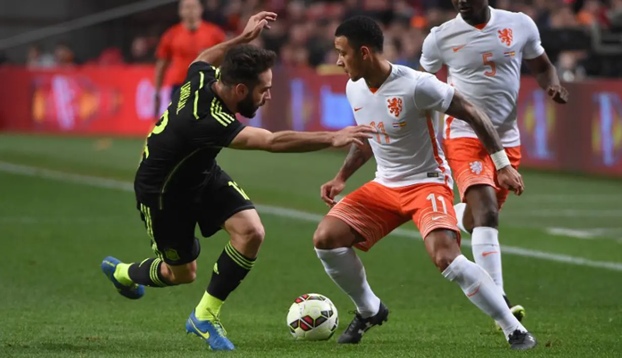 Gelandang Belanda, Memphis Depay (tengah) berusaha melewati pemain Spanyol Daniel Carvajal pada laga persahabatan di Amsterdam Arena, Belanda, Rabu (1/4/2015). Belanda menang 2-0 atas Spanyol. (AFP PHOTO/Emmanuel Dunand)