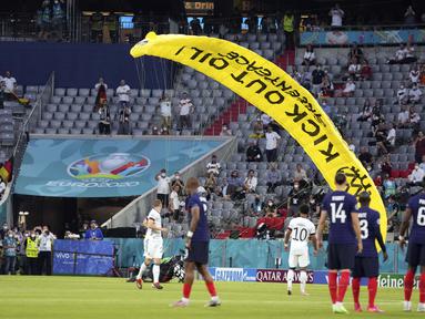 Seorang aktivis LSM lingkungan hidup Greenpeace tiba-tiba muncul dari angkasa dengan sebuah paraglider saat laga Grup F Piala Eropa 2020 timnas Jerman dan timnas Perancis hendak dimulai. (Foto: AP/Pool/Matthias Schrader)