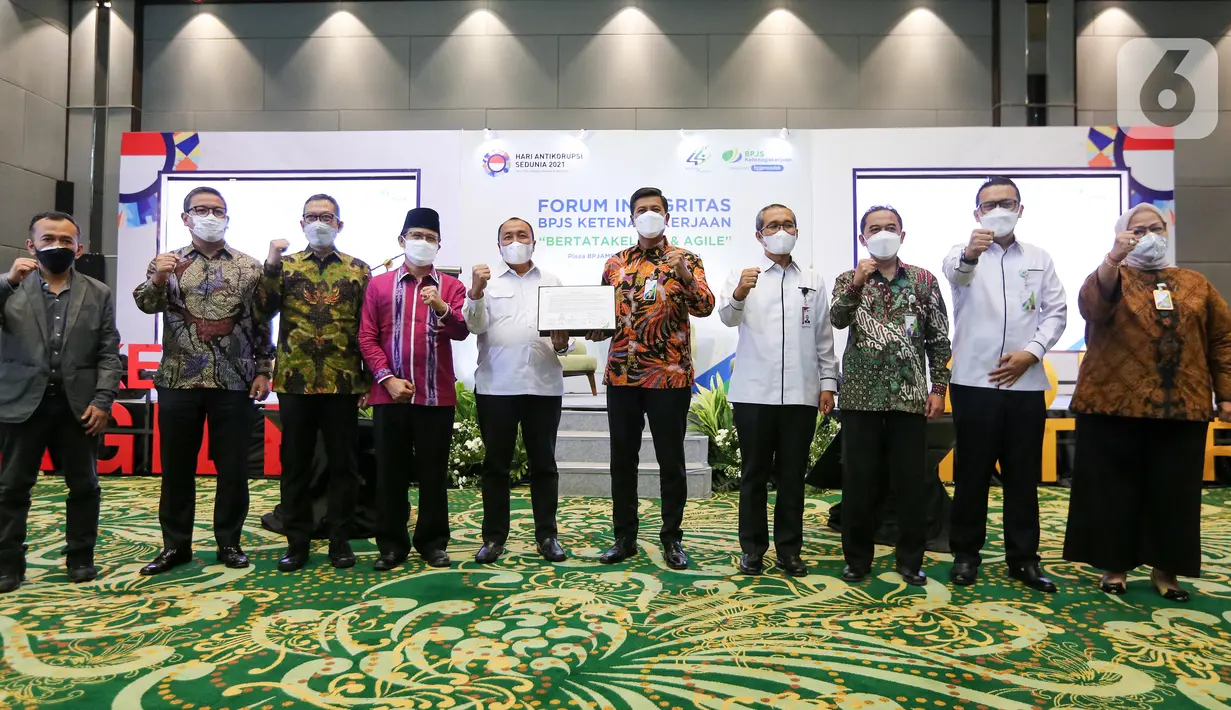 Jajaran Direksi dan Dewan Pengawas BPJAMSOSTEK, Anggota Dewan Jaminan Sosial Nasional (DJSN), dan KPK foto bersama usai menandatangani Sistem Manajemen Anti Penyuapan (SMAP) dan pengembangan kanal pelaporan WBS di Plaza BPJAMSOSTEK, Jakarta (13/12/2021). (Liputan6.com/Fery Pradolo)