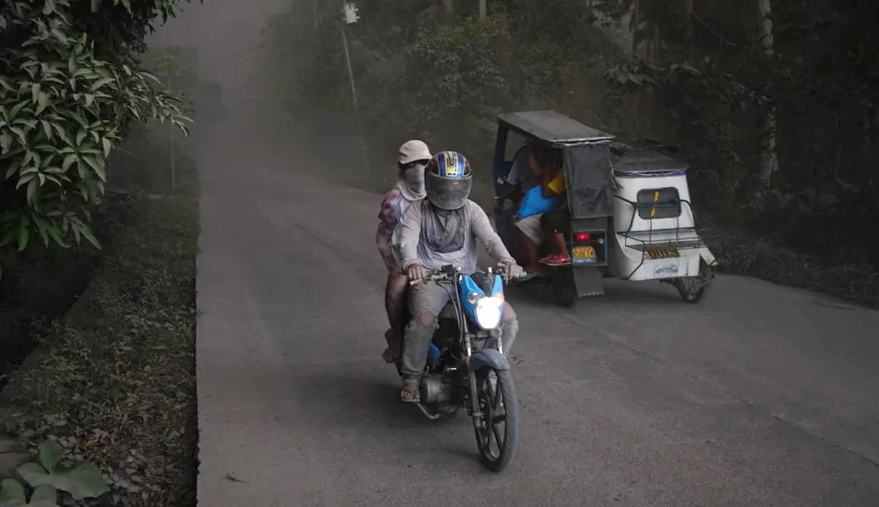 Warga beraktivitas menggunakan masker saat Gunung Mayon mengeluarkan asap tebal di Kota Legazpi, Provinsi Albay, Filipina, Selasa (23/1). Institut Vulkanologi dan Seismologi Filipina meningkatkan statusnya menjadi siaga empat. (AP Photo/Dan Amaranto)