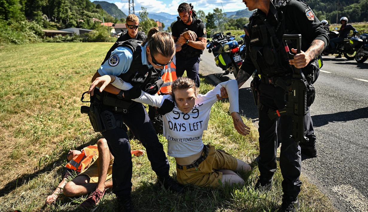 Polisi Prancis memindahkan sejumlah pengunjuk rasa lingkungan setelah aksi protes mereka menghentikan sementara balapan pada etape ke-10 Tour de France, antara Morzine dan Megeve, di Pegunungan Alpen Prancis, pada 12 Juli 2022. (AFP/Marco Bertorello)