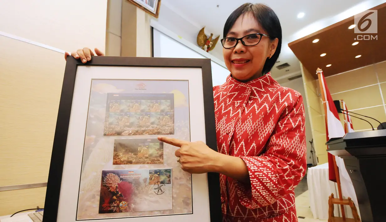 Karyawan Kementerian Komunikasi dan Informatika menunjukkan prangko bersama Indonesia Singapura usai peluncuran di Jakarta, Kamis (7/9). Ini bagian perayaan 50 tahun hubungan Indonesia-Singapura. (Liputan6.com/Helmi Fithriansyah)