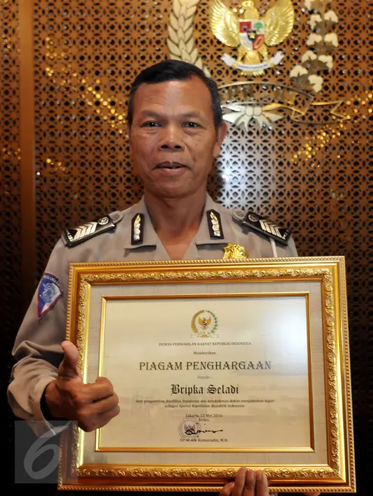 Bripka Seladi, anggota Polres Malang Kota yang menjalani pekerjaan sampingan sebagai pemulung menunjukkan piagam penghargaan, di Jakarta, Senin (23/5). Seladi mendapat penghargaan sebagai polisi teladan dari Ketua DPR RI. (Liputan6.com/Johan Tallo)