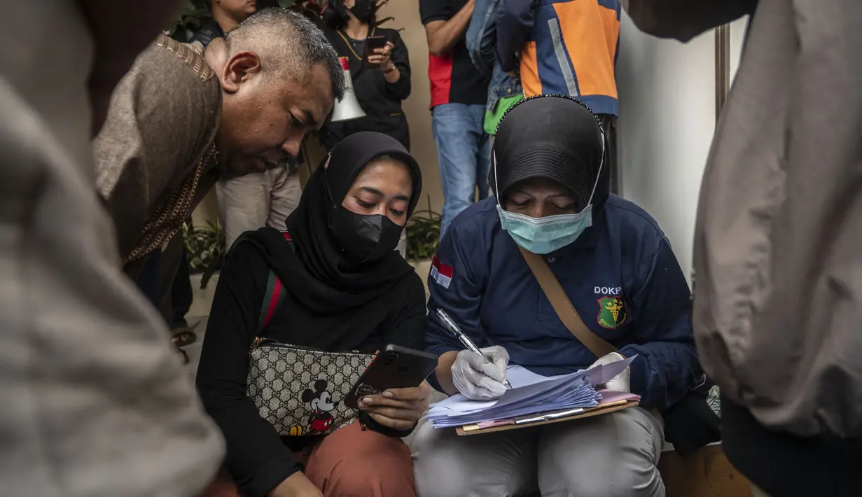 Polisi mengidentifikasi kerabat korban saat mereka mengantri jenazah di Malang, Jawa Timur pada 2 Oktober 2022. Sedikitnya 174 orang tewas di stadion sepak bola Indonesia ketika ribuan penggemar tuan rumah yang marah menyerbu lapangan dan polisi menanggapi dengan gas air mata yang memicu desak-desakan, kata pihak berwenang pada 2 Oktober. (AFP/Juni Kriswanto)