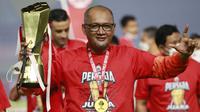 Pelatih Persija Jakarta, Sudirman, mengangkat trofi usai menjuarai Piala Menpora 2021 di Stadion Manahan, Solo, Minggu (25/4/2021). Persija mengalahkan Persib dengan agregat 4-1. (Bola.com/M Iqbal Ichsan)