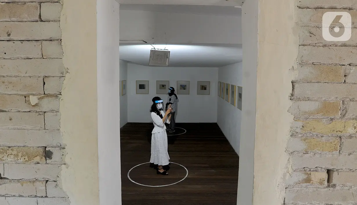 Pengunjung berjaga jarak fisik saat melihat pameran karya pelukis Hanafi berjudul 60 tahun dalam studio di Galerikertas, Depok, Jawa Barat, Selasa (7/7/2020).  Pameran tersebut menerapkan protokol kesehatan guna mencegah penyebaran COVID-19. (merdeka.com/Arie Basuki)