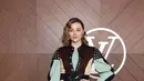 Chloe Grace Moretz mengenakan atasan long sleeve warna hijau mint pada bagian lengan dan coklat pada bagian depan dengan inner top hijau mint. Dipadukan short pants leather hitam senada dengan micro bag dan knee boots nya. [dok. Louis Vuitton]