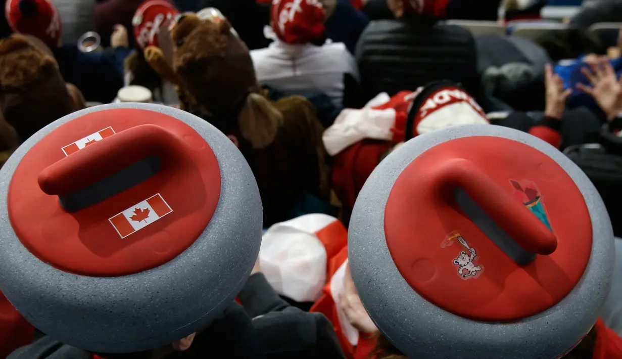 Penonton mengenakan atribut kepala unik saat menyaksikan cabang curling ganda campuran antara Kanada dan Swiss pada Olimpiade Musim Dingin 2018 di Gangneung, Korsel, Selasa (13/2). Olimpiade ini berlangsung hingga 25 Februari mendatang. (AP/Aaron Favila)