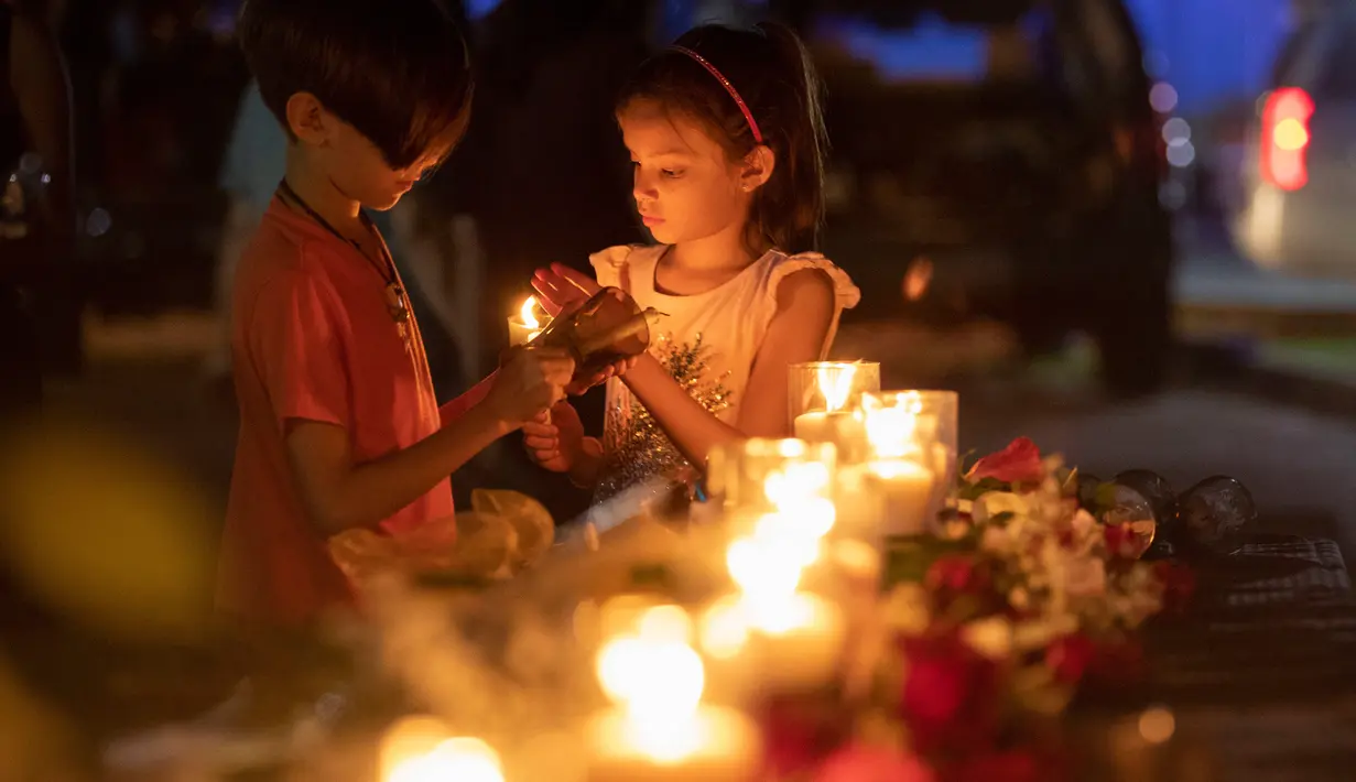 Lucrecia Martinez (7) dan saudara laki-lakinya Luciano (9) menyalakan lilin untuk mengenang korban penembakan di sekolah Santa Fe, Texas, Amerika serikat, Jumat (18/5). (Stuart Villanueva/The Galveston County Daily News via AP)