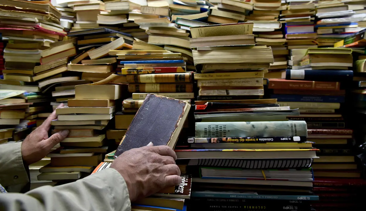 Jose Alberto Gutierrez memeriksa buku koleksinya yang ada di perpustakaan rumahnya di Bogota, 18 Mei 2017. Koleksi buku Gutierrez beragam, mulai dari buku-buku pelajaran hingga novel karya maestro Kolombia, gabriel Garcia Marquez. (GUILLERMO LEGARIA/AFP)