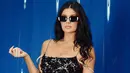 <p>Kylie Jenner tampil menggunakan spaghetti strap long dress lace warna hitam. Sambil membawa handbag hitam dan kacamata hitamnya. [Dok. MiuMiu]</p>