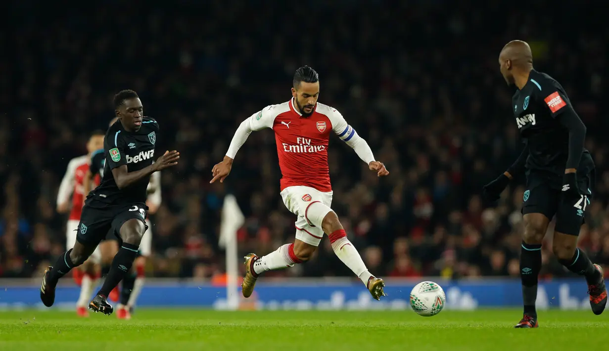 Pemain Arsenal Theo Walcott menggiring bola melewati pemain West Ham United pada laga perempat final Piala Liga Inggris di Emirates Stadium, Selasa (20/12). Gol tunggal Danny Welbeck memberikan Arsenal kemenangan 1-0 atas West Ham. (AP /Alastair Grant)