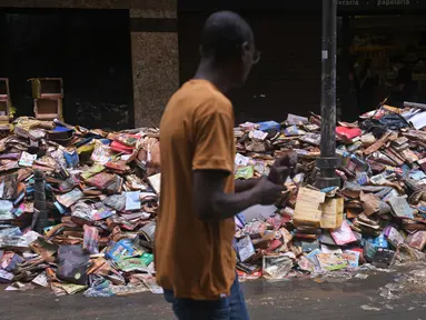 Ribuan buku rusak terlihat di jalan setelah hujan lebat membanjiri toko buku di Petropolis, Brasil, 19 Februari 2022. Sebanyak 136 jenazah telah diidentifikasi hingga kini, menurut pejabat pertahanan sipil, di kota wisata yang biasanya indah, sekitar 60 km utara Rio de Janeiro. (MAURO PIMENTEL/AFP)