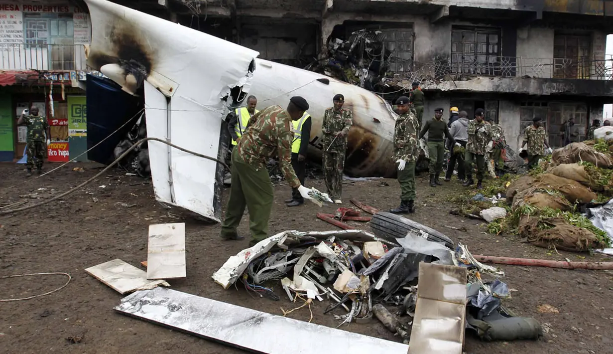 Petugas keamanan setempat langsung melakukan evakuasi terhadap bangkai pesawat kargo jenis Fokker 50 yang terjatuh dan terbakar di pinggiran Nairobi, Kenya, (2/7/2014). (REUTERS/Thomas Mukoya)