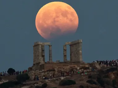 Gerhana bulan parsial terlihat di atas kuil Poseidon di Cape Sounion, Yunani, Senin (7/8). Gerhana bulan parsial terjadi ketika bumi bergerak di antara bulan dan matahari, tapi tidak persis dalam satu garis. (AP Photo/Petros Giannakouris)