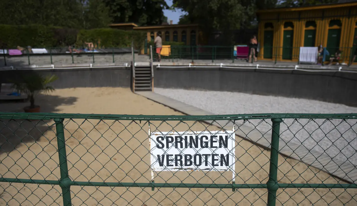 Tanda bertuliskan "Dilarang melompat" digantung di pagar bekas kolam renang perempuan yang dikosongkan dan diisi pasir di pemandian air panas Bad Fischau, 50 km selatan Wina, di Bad Fischau, Austria Hilir, pada 18 Agustus , 2022. Pemandian air panas Belle Epoque Bad Fischau yang terkenal harus menutup beberapa kolam karena beberapa mata air yang memasoknya telah mengering karena kekeringan di tengah perubahan iklim. (Alex HALADA / AFP)