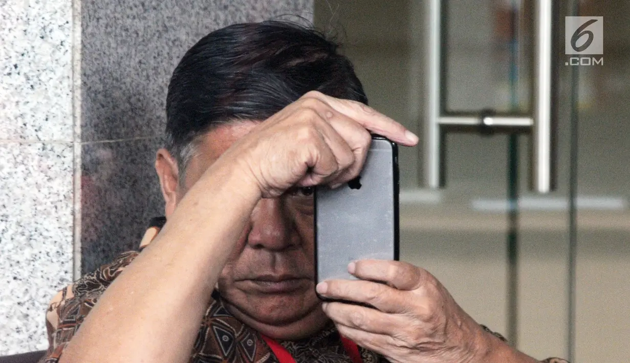 Mantan Bupati Buton Laode Muhammad Sjafei Kahar bermain ponsel saat menunggu untuk menjalani pemeriksaan di lobi gedung KPK, Jakarta, Rabu (17/7). Sjafei Kahar merupakan ayah Bupati Buton Selatan nonaktif Agus Feisal. (Merdeka.com/Dwi Narwoko)
