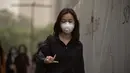 Seorang wanita berjalan sambil mengenakan masker saat badai debu menerjang kota Beijing, China, Kamis (4/5). Diperkirakan, badai deb akan mencakup sebagian besar wilayah barat laut China. (Nicolas ASFOURI/AFP)