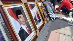Pedagang memasukkan foto resmi kenegaraan Presiden Joko Widodo atau Jokowi dan Wakil Presiden Jusuf Kalla ke dalam pigura di Pasar Baru, Jakarta, Sabtu (25/10/2014). (Liputan6.com/Miftahul Hayat)