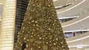 Pengunjung melintas di dekat pohon Natal di Senayan City, Jakarta, Selasa (14/12/2021). Senayan City menghadirkan  Giant Golden Christmas Tree instalasi yang berdiri megah sebagai ikonik momen Natal dengan tinggi mencapai 18 meter dan dikelilingi oleh Golden Christmas Balls. (Liputan6.com/Fai