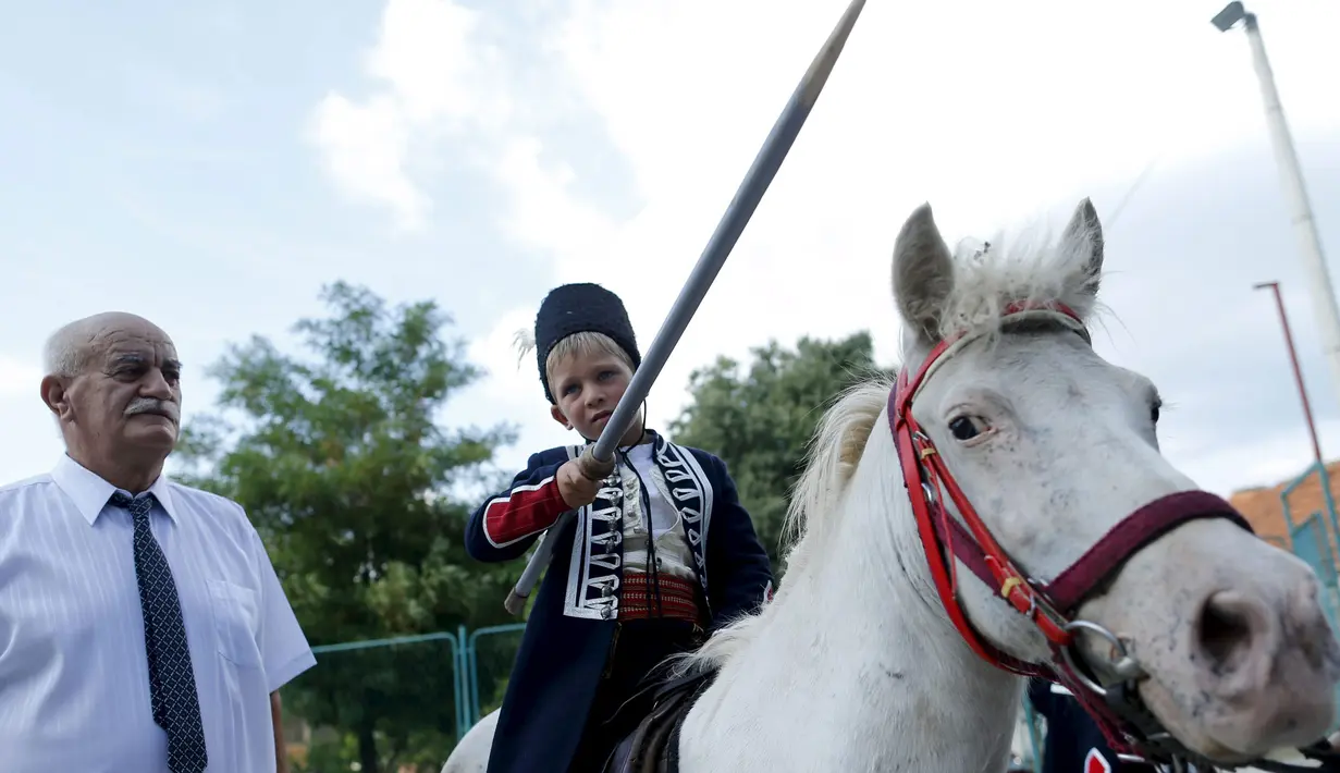 Seorang anak berpose sambil menaiki kuda sebelum mengikuti turnamen tradisional Alka di desa Vuckovici, Kroasia, Minggu (23/8/2015). Alka adalah turnamen yang diselenggarakan setiap bulan Agustus sejak 1955. (REUTERS/Antonio Bronic)