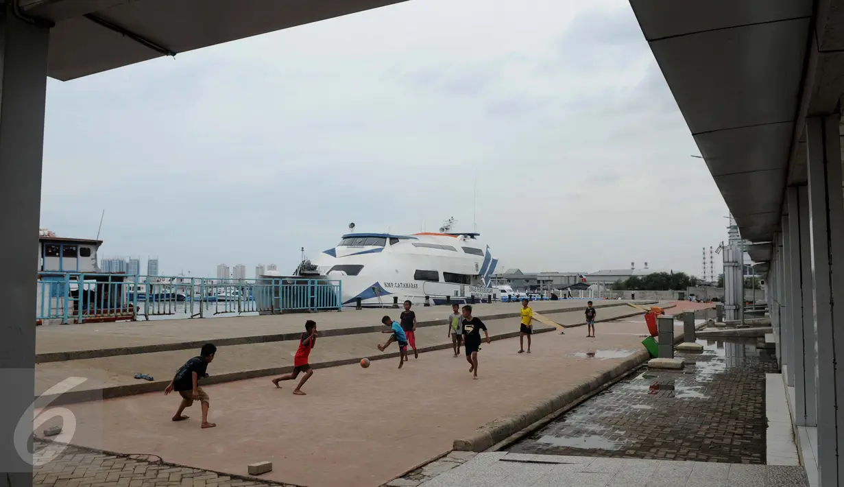 Seorang anak mencoba mengoper bola pada temannya saat bermain bola di pelataran Pelabuhan Kali Adem, Muara Angke, Jakarta, Rabu (4/1). Mereka memanfaatkan Kali Adem sebagai arena bermain selama mengisi masa liburan sekolah. (Liputan6.com/Gempur M Surya)