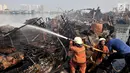 Petugas pemadam kebakaran melakukan pendinginan kapal yang ludes dilalap api di Pelabuhan Muara Baru, Jakarta, Minggu (24/2). Saat ini, polisi juga telah memeriksa tujuh saksi terkait kebakaran tersebut. (Merdeka.com/Iqbal Nugroho)