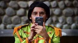 Seorang peserta mengambil gambar saat kegiatan untuk memecahkan rekor dunia dengan jumlah terbesar orang mengenakan pakaian dan bergaya seperti  The Beatles di sebuah taman di Mexico City, Meksiko 28 November 2015. (AFP PHOTO/ALFREDO ESTRELLA)