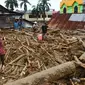 Orang-orang berjalan di atas puing-puing di daerah yang terkena banjir bandang di Masamba, Sulawesi Selatan, Rabu (15/7/2020). Banjir bandang akibat tingginya curah hujan tersebut mengakibatkan 16 orang meninggal dunia dan puluhan warga dilaporkan masih dalam pencarian. (AP/Khaizuran Muchtamir)