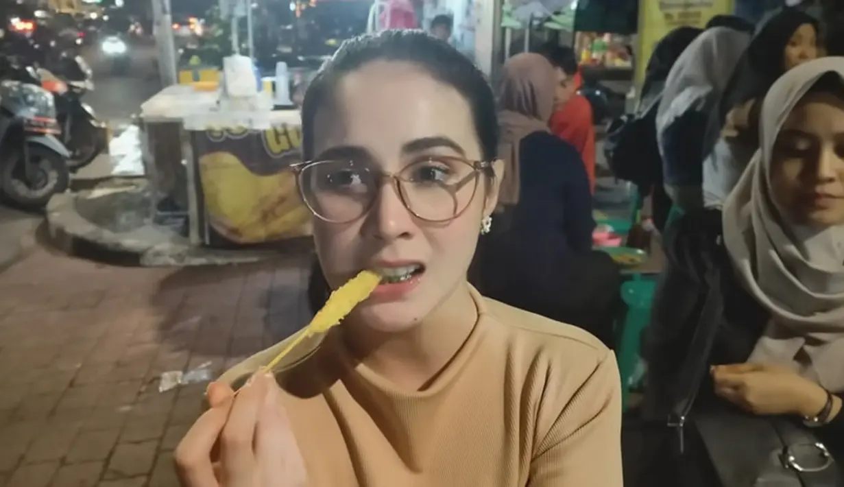 Selesai menyantap gulai tikungan, hingga sate, langsung menyantap jajanan favoritnya, yaitu telor gulung. Tidak berhenti sampai disitu, Arumi juga menyantap tahu gejrot. [Youtube/arumibachsin_94]