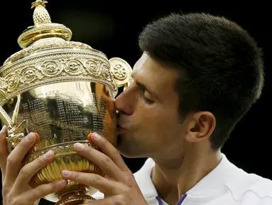 Petenis Serbia, Novak Djokovic mencium trofi kemenangannya setelah mengalahkan petenis Swiss, Roger Federer di babak final tunggal putra Wimbledon 2015, London, Minggu (12/7). Ini adalah gelar Wimbledon ketiga bagi Djokovic.  (REUTERS/Stefan Wermuth)