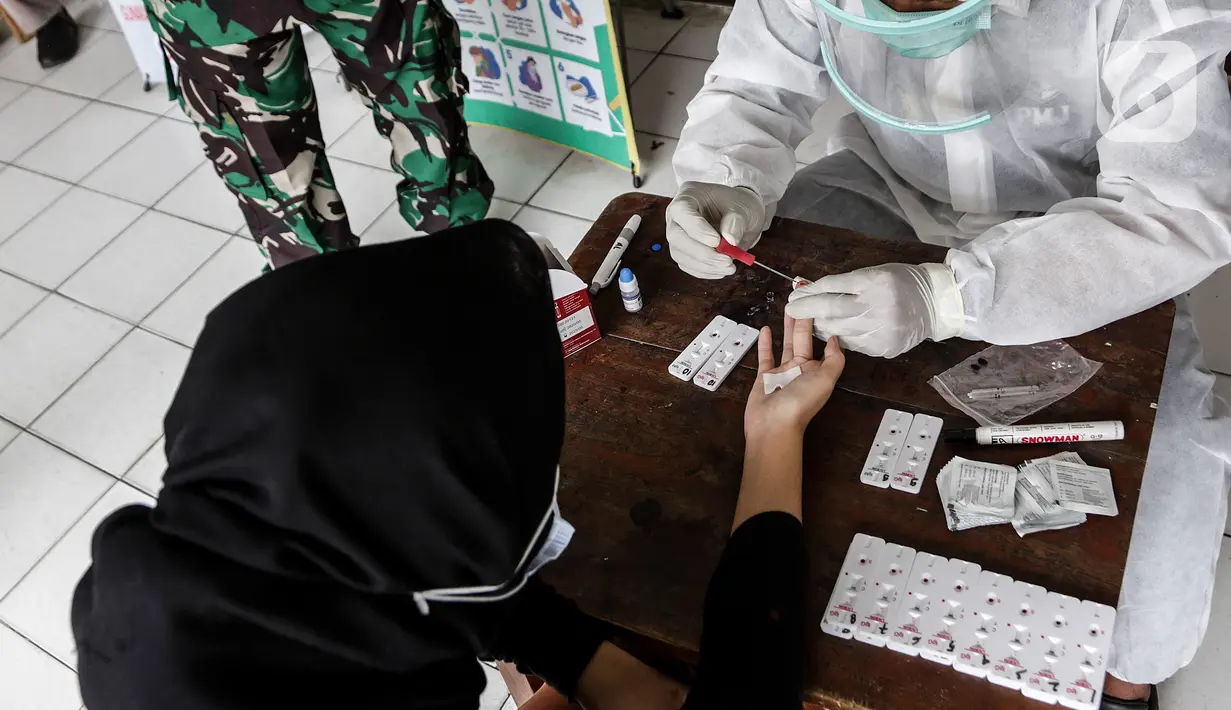Petugas kesehatan mengambil sampel darah saat rapid test massal Covid-19 di SDN Petamburan 01, Petamburan, Jakakrta, Jumat (27/11/2020). Rapid test massal ini digelar sebagai langkah petugas dalam melakukan testing, dan tracing setelah adanya kerumunan di Petamburan. (Liputan6.com/Johan Tallo)