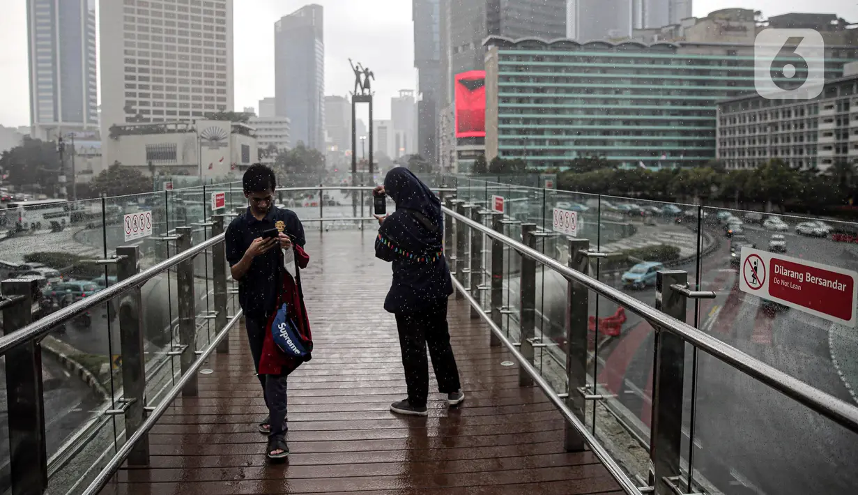 Warga berjalan di JPO Bundaran HI, Jakarta, Rabu (28/12/2022). Walau sempat disebutkan ada potensi badai dahsyat yang melanda kawasan Jakarta–Bogor–Depok–Tangerang–Bekasi (Jabodetabek) pada hari ini, warga Jakarta terpantau masih banyak beraktivitas di luar ruangan. (Liputan6.com/Faizal Fanani)