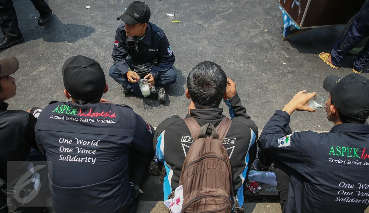 Buruh beristirahat sambil menikmati minuman di trotoar jalan di kawasan Istana Negara, Jakarta, Kamis (15/9). Ribuan buruh dari berbagai elemen organisasi menyatakan penolakan mereka terhadap paket kebijakan ekonomi jilid IV. (Liputan6.com/Faizal Fanani)