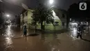 Warga melewati rumah yang tergenang banjir di jalan Bank, Jakarta Selatan, Selasa (4/10/2022). Hujan yang mengguyur wilayah Ibu Kota Jakarta mengakibatkan banjir menggenangi kawasan Kemang, Jakarta. (Liputan6.com/Johan Tallo)