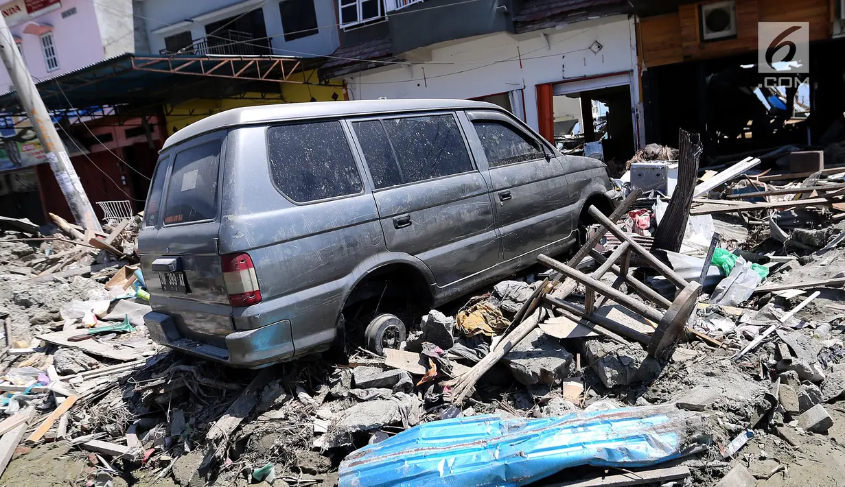 Sebuah mobil Mitsubishi Kuda menjadi incaran jarahan korban gempa dan tsunami di Palu Grand Mal, Palu, Jumat (5/10). Warga korban gempa bumi mengambil ban dan interior mobil. (Liputan6.com/Fery Pradolo)