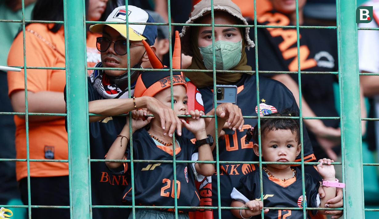 Suporter Cilik saat menyaksikan pertandingan Persija Jakarta melawan Arema FC pada laga BRI Liga 1 di Stadion Patriot Candrabhaga, Bekasi, Minggu (12/2/2023). Orang tua yang juga fans Persija sudah mulai menularkan kecintaan mereka pada Macan Kemayoran sejak dini. (Bola.com/M Iqbal Ichsan)