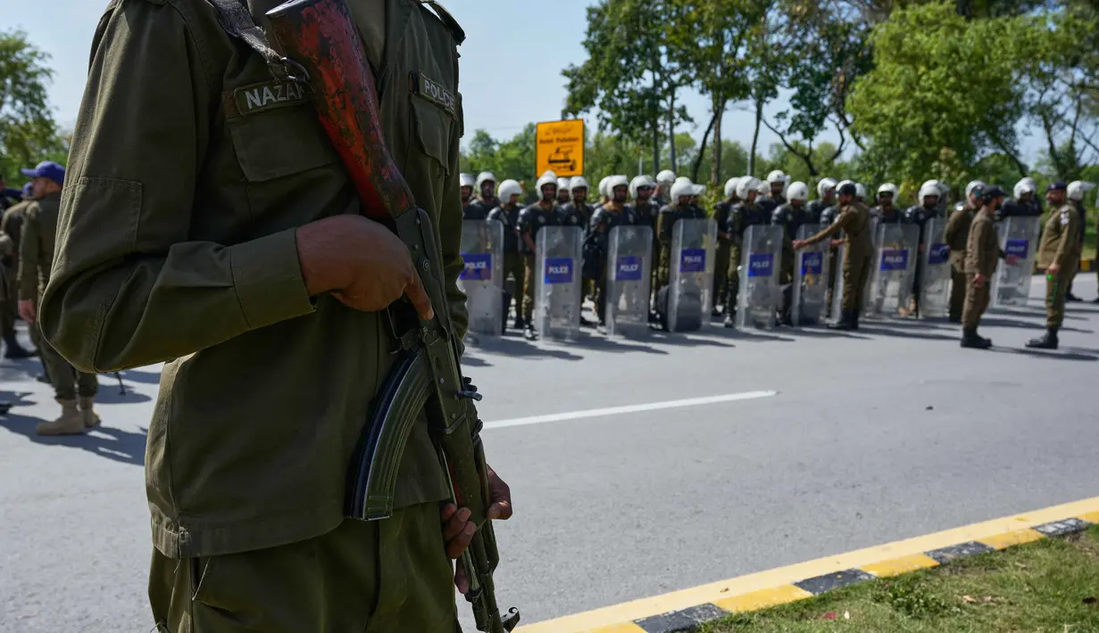 Pertemuan ini menyusul kesepakatan gencatan senjata sementara selama dua minggu di tengah ketegangan tinggi antara Iran dan Amerika Serikat dengan fokus utama pada keamanan di Selat Hormuz. Tampak dalam foto, seorang petugas polisi berjaga sementara yang lain mengikuti pengarahan sebelum penugasan mereka di Islamabad, Pakistan, untuk memastikan keamanan menjelang kemungkinan negosiasi antara Iran dan Amerika Serikat, Jumat 10 April 2026. (AP Photo/Anjum Naveed)