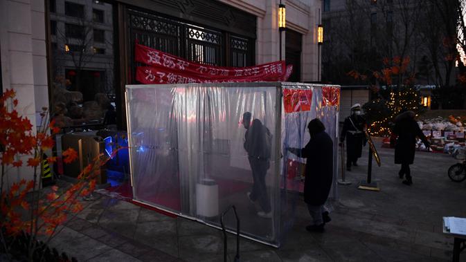 Warga melewati terowongan dengan disinfektan sebagai perlindungan dari Virus Corona COVID-19 di pintu masuk bangunan di Tongzhou, Beijing Timur, Rabu (18/2/2020). Korban meninggal akibat terinfeksi virus corona COVID-19 di seluruh dunia hingga Rabu (19/2) mencapai 2.005 orang. (GREG BAKER/AFP)