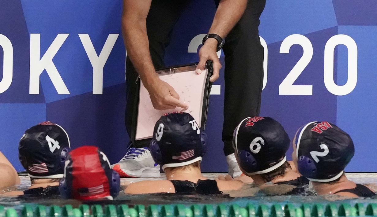 Pemain polo air Amerika Serikat mendengarkan pelatih kepala Adam Krikorian saat waktu istirahat dalam pertandingan babak penyisihan polo air putri Olimpiade Tokyo 2020 melawan Hungaria, Rabu (28/7/2021). (Foto: AP/Mark Humphrey)