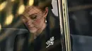 Kate Middleton berada di dalam mobil saat menghadiri prosesi persemayaman Ratu Elizabeth II di Westminster Hall di London (14/9/2022). Kate Middleton yang mendapat gelar baru sebagai Princess of Wales memakai bros berlian dan mutiara berbentuk daun. (AFP/Marco Bertorello)