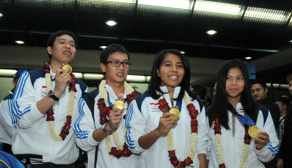 Pebulutangkis ganda putra dan putri peraih emas Asian Games 2014, Hendra Setiawan/Mohammad Ahsan dan Nitya Krishinda/Greysia Polii (dari kiri ke kanan) berpose di Bandara Soekarno-Hatta, Selasa (30/9/2014). (Liputan6.com/Helmi Fithriansyah)