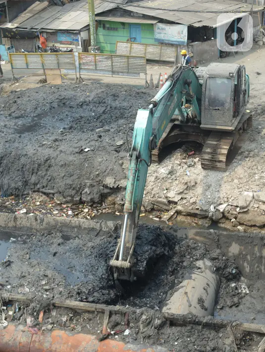 Alat berat mengangkat material endapan lumpur di Kampung Nelayan Cilincing, Jakarta Utara, Kamis (2/9/2021). Pengerukan dilakukan untuk mengurangi pendangkalan di muara teluk Jakarta serta penataan sandaran kapal-kapal tradisional. (merdeka.com/Imam Buhori)