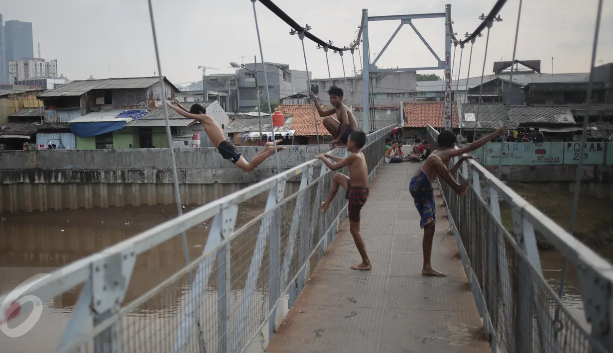 Seorang anak melompat dari atas jembatan dan berenang di aliran kali besar Banjir Kanal Barat, Jakarta, Sabtu (11/3). Minimnya pengawasan orang tua membuat mereka bermain di tempat berbahaya dan mengancam keselamatan. (Liputan6.com/Faizal Fanani)