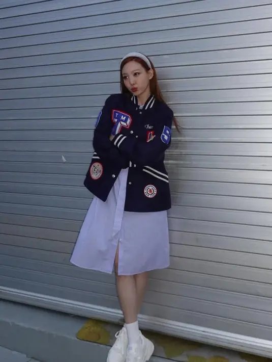 Nayeon tampil mengenakan jaket baseball oversize waena navy dengan hiasan patch. Dipadukan mini dress putih.  [@nayeonyny]