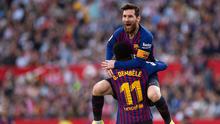 Penyerang Barcelona Lionel Messi memeluk rekan setimnya Ousmane Dembele usai mencetak gol ke gawang Sevilla pada laga La Liga di Stadion Ramon Sanchez Pizjuan, Sevilla, Sabtu (23/2). Barcelona menang 4-2. (JORGE GUERRERO/AFP)