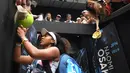 Petenis Jepang Naomi Osaka menandatangani benda yang disodorkan penonton usai mengalahkan petenis Republik Ceko Marie Bouzkova pada Australia Terbuka di Melbourne, Australia, Senin (20/1/2020). Penonton menyodorkan topi, bendera, hingga bola untuk ditandatangani Naomi. (AP Photo/Andy Brownbill)