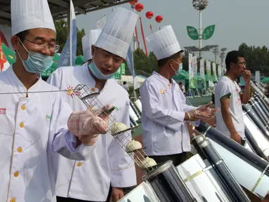 Para koki memasak roti menggunakan tabung logam dan kaca yang dipanaskan oleh cermin melengkung untuk menangkap sinar matahari di Dezhou, Shandong Timur, Cina, 2 Agustus 2018. Koki memasak dengan kompor tenaga surya. (AP Foto/Fu Ting)